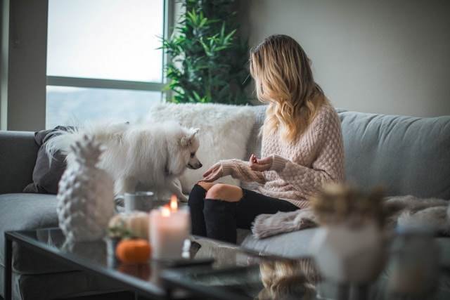 A lady sitting at home with her dog nice and snug because the plumber fixed the heating